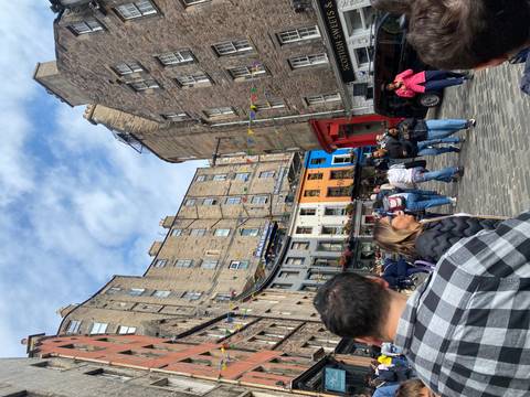 A bustling street scene with historic buildings and people walking.