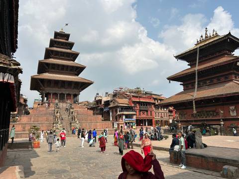       Historic square with temples and people walking around.
  