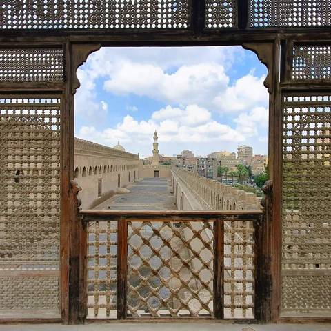       View of Cairo from a decorative window with skyline and domes.
  