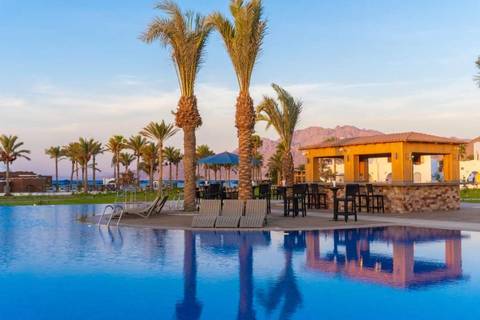       Resort pool area with palm trees and mountains in the background.
  