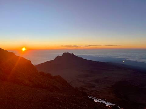 Kilimanjaro landscape at sunrise with dramatic peaks and cloud cover.