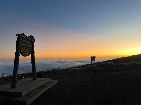 Sunset view from Kilimanjaro with scenic clouds and signage.