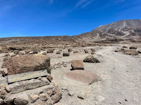 Mountainous landscape with a directional sign pointing to Kibo Hut and Horombo Hut.