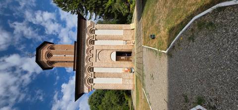       Historical church with intricate brickwork and surrounding gardens.
  