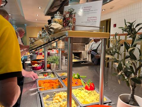 Buffet with various dishes and people serving food.