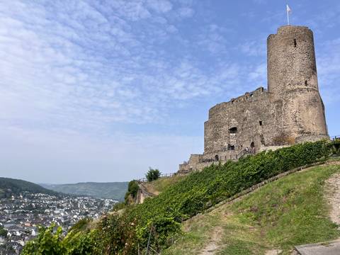 Ruins of an ancient fortress overlooking a town and surrounding landscape.