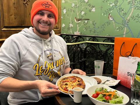 Person seated at a table with a plate of food and a salad.