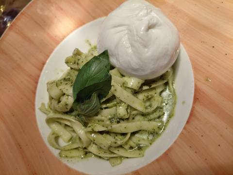 Plate of pasta with pesto sauce and a ball of mozzarella.