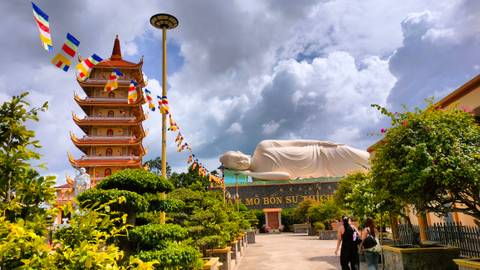 Reclining Buddha statue next to a pagoda under a cloudy sky.