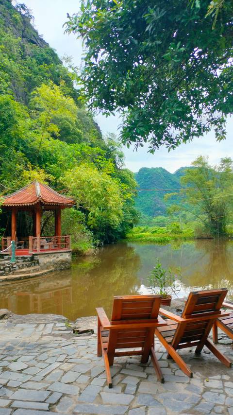 Gazebo by a pond in a lush green setting.
