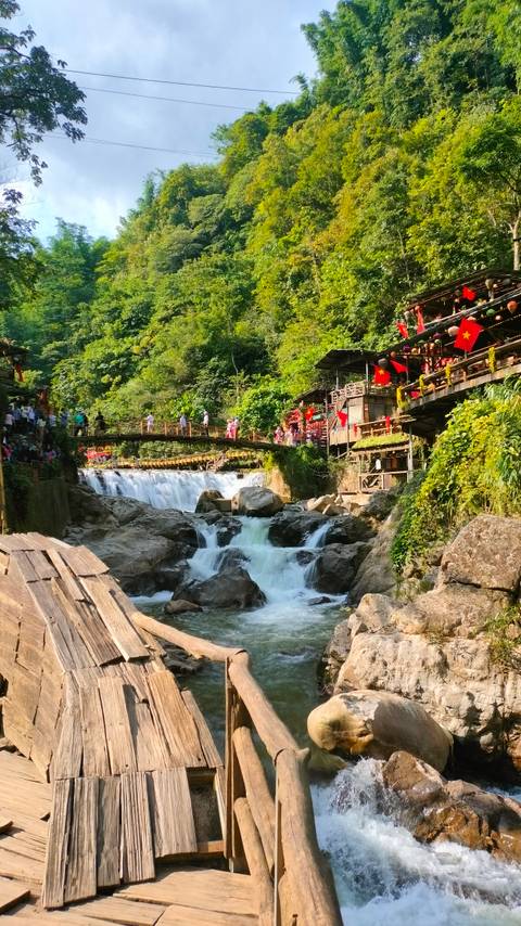Idyllic scene of a waterfall with a bridge and tourists.