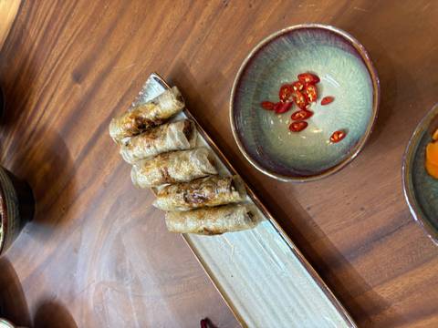       Spring rolls plated with decorative chili pepper slices.
  
