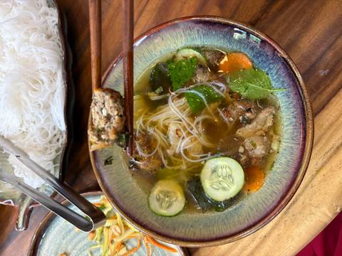       A delicious pho noodle soup with meatballs and fresh vegetables.
  
