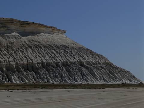       Rock formation with stratified layers against a blue sky.
  