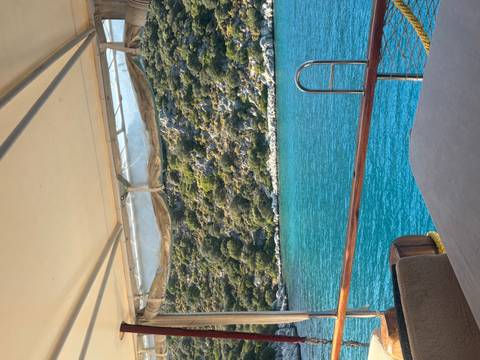 View from a boat of a turquoise sea and rocky hills.