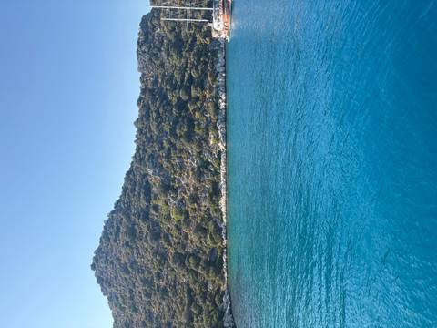 Calm blue sea with a hillside in the background.