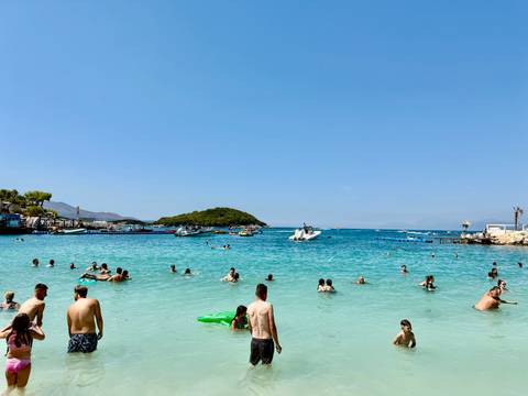 Crowded beach with people swimming and relaxing.