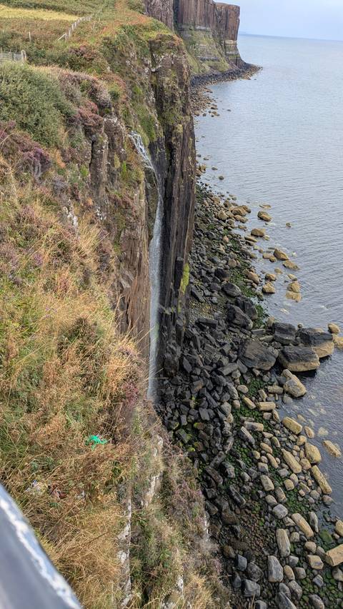 Cliffside view of a waterfall dropping into the ocean.
