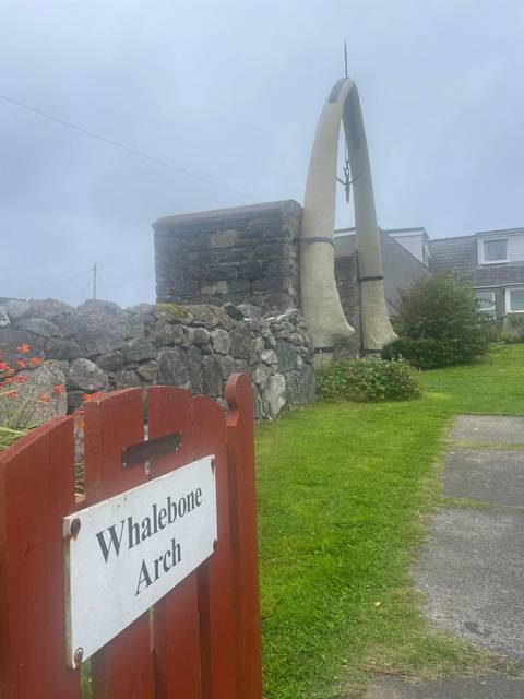 Stone wall with a gate and large animal bones displayed.