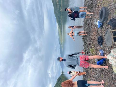       People by a lake, some entering the water.
  