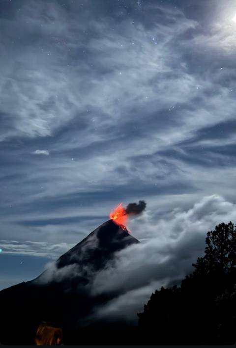 A volcano erupting under a night sky with stars.