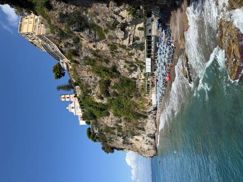Scenic coastline with beachgoers and cliffside buildings.