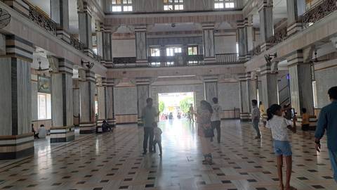 Interior of a grand building with people walking around.