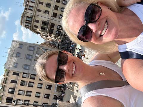 Two women smiling with a busy street in the background.