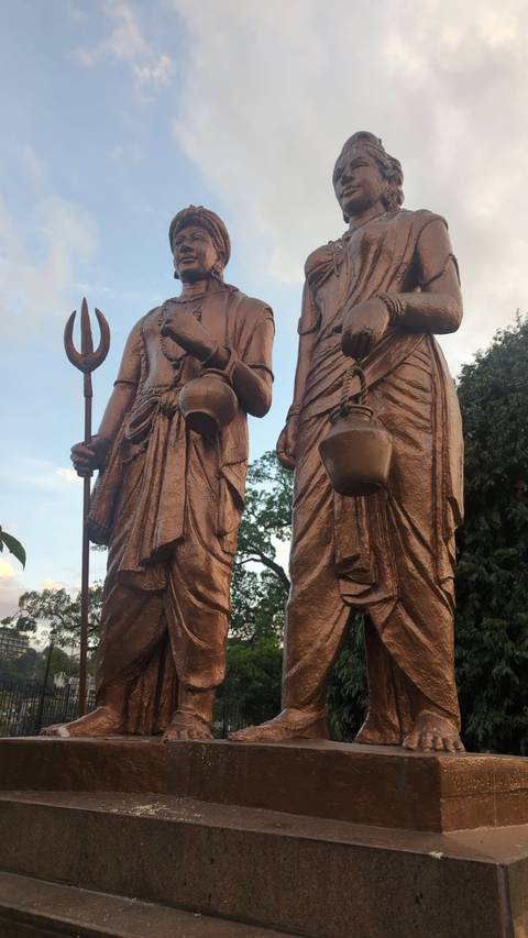       Statue of two historical figures with trees in the background.
  