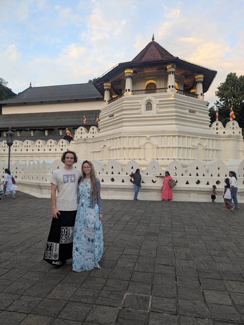 Couple visiting a temple with people in the background.