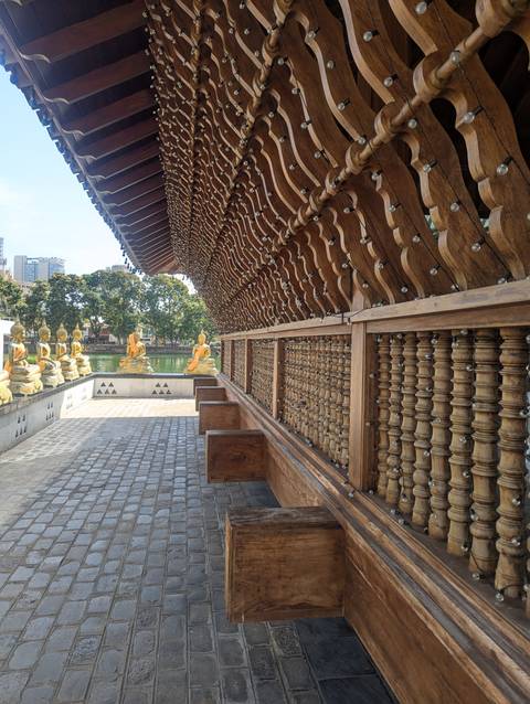       Buddha statues lined along a wooden railing.
  