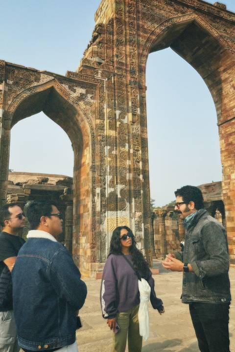       People standing near ancient stone carvings and arches.
  