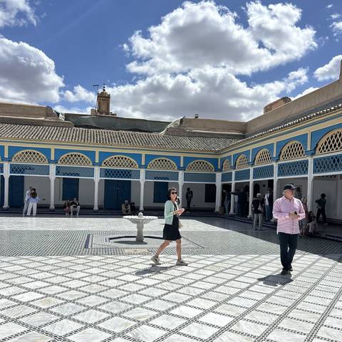      People walking in a traditional courtyard with intricate tile flooring.
  