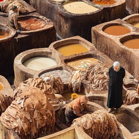       Workers at a traditional tannery with vats.
  