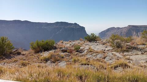 Rocky mountain landscape with clear sky and dry vegetation.