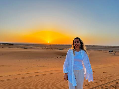 Person standing in desert at sunset.