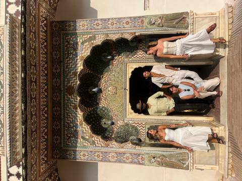      Group posing in front of an ornately decorated doorway.
  