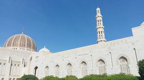 A grand mosque with a large dome and minaret under a clear blue sky.