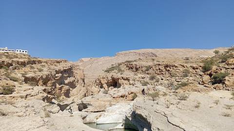 A rocky gorge with sparse vegetation and water at the bottom.