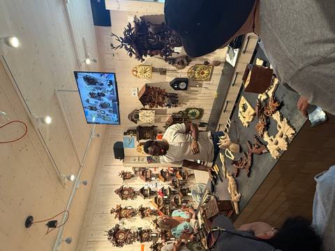 A craft shop with a variety of clocks and a craftsman demonstrating.