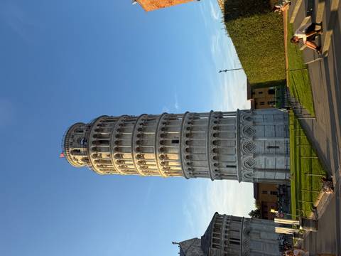 The Leaning Tower of Pisa with people relaxing on the grass.