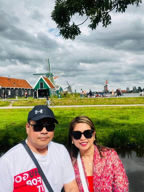       Couple with a backdrop of windmills in a scenic countryside.
  