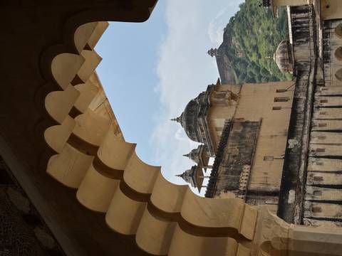       Architectural view through a decorative archway with a fort in the distance.
  