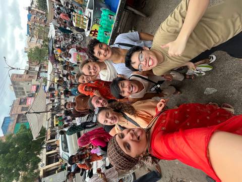       Group of travelers smiling in a bustling street market.
  