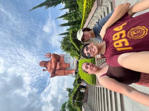       Three travelers posing in front of a large Shiva statue.
  