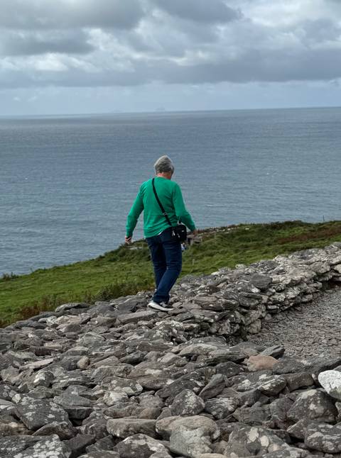 Person walking on a stone wall by the ocean.