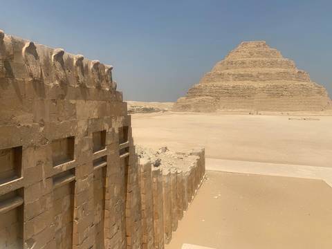 Ancient pyramid and an old stone structure in a desert.
