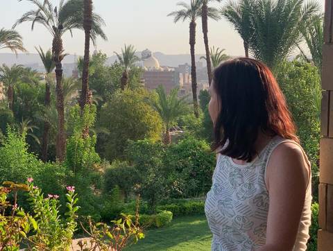 Woman looking out over a lush garden to a cityscape.