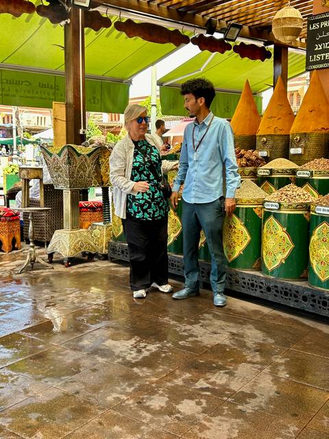       Two people standing near spice stalls in a market.
  