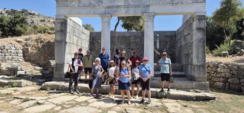      Group of tourists posing in front of ancient ruins.
  
